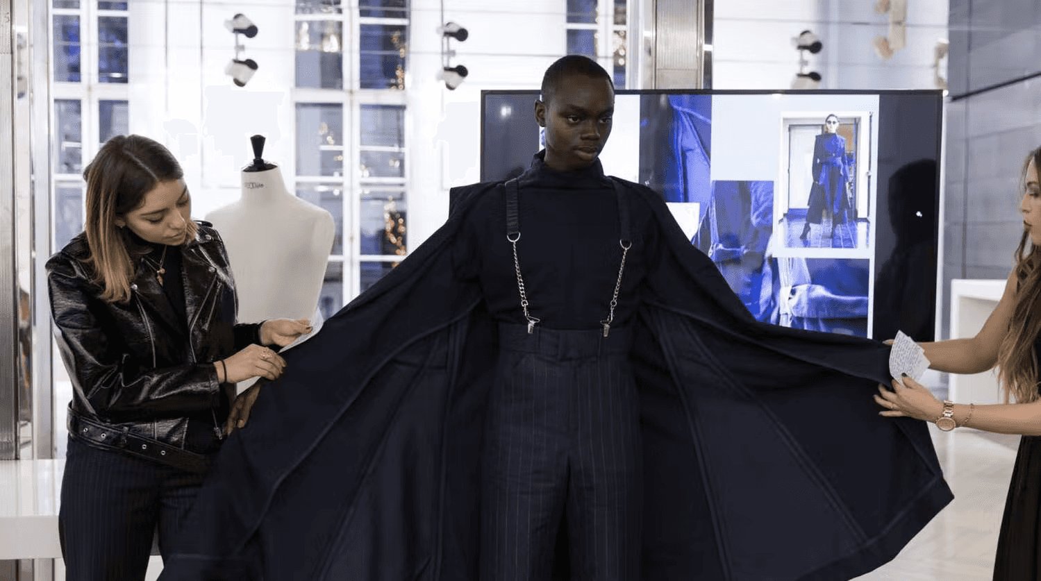 Model being fitted in a new garment by two women for a fashion show